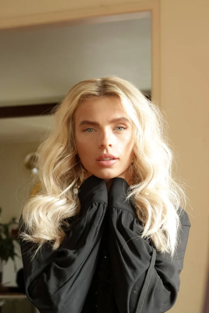 Blond woman staring into camera with light.