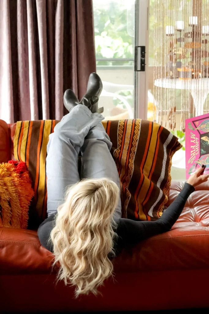Blond woman laying on red couch and holding a record.