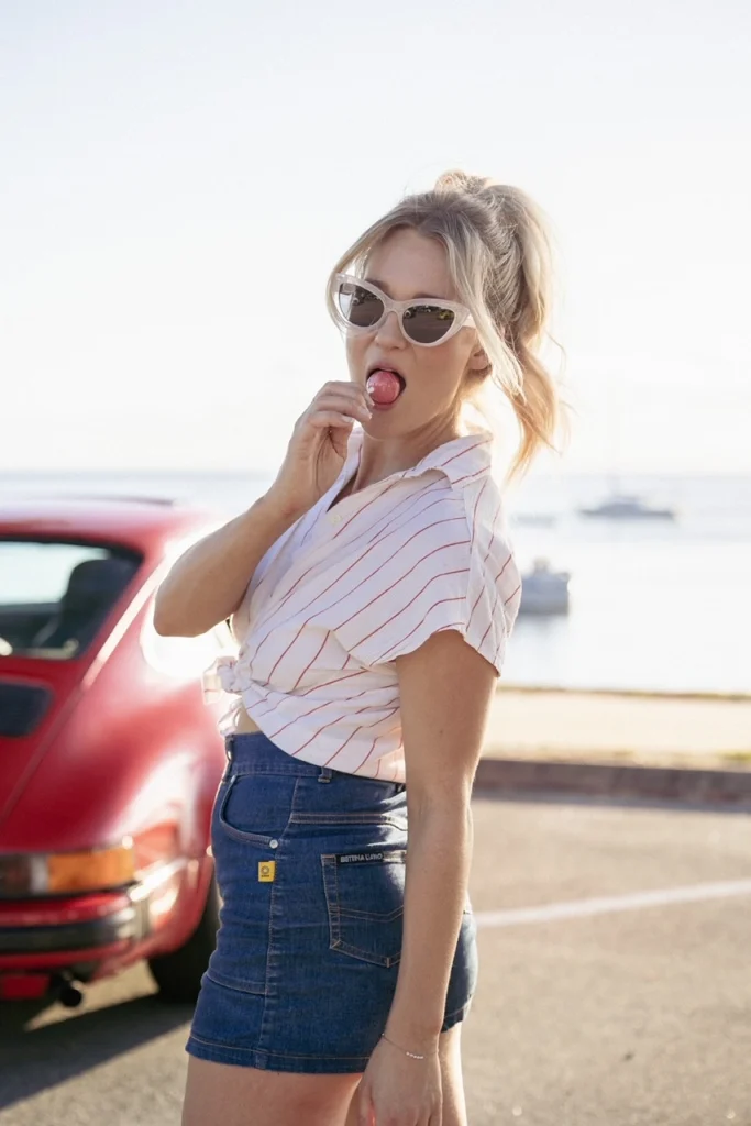 Woman wearing stripy shirt with car in background.