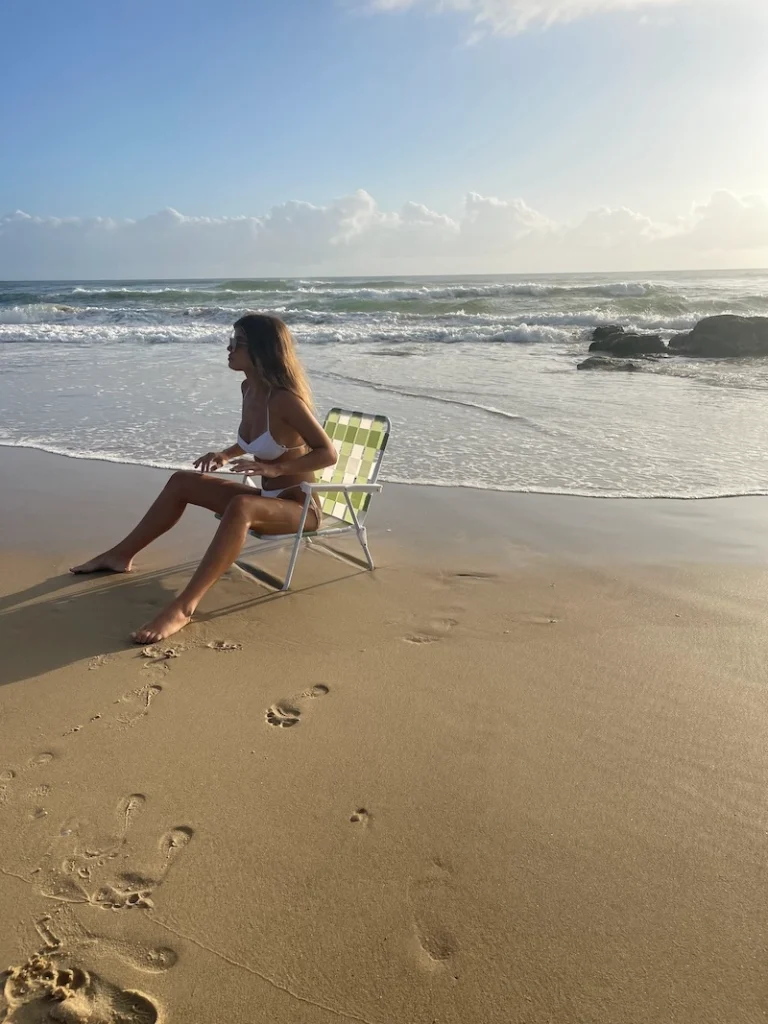 Woman sitting on folded chair on the shoreline.